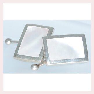 A pair of mother of pearl cufflinks on a white surface.